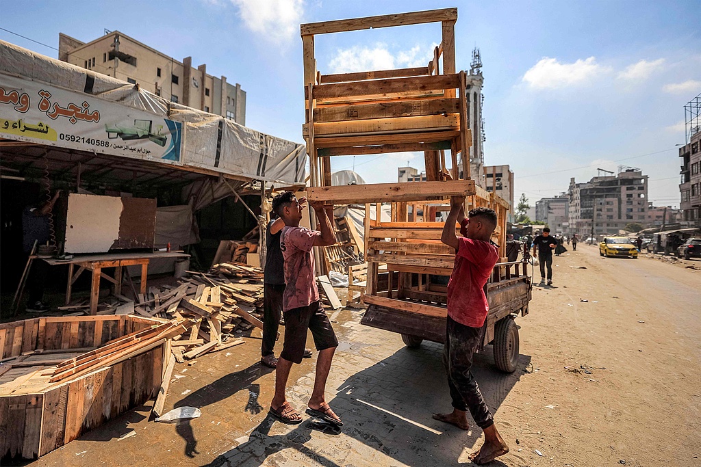 Men load newly fabricated school desks made from re-purposed old wooden pallets and scrap wood onto a motor cart from a workshop in the Rimal neighborhood of Gaza City, September 14, 2026. /VCG