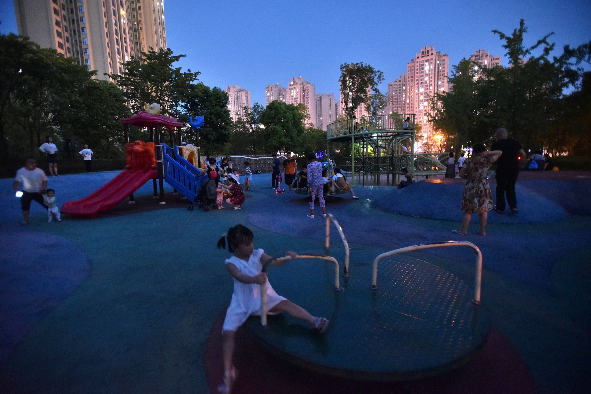 A neighborhood playground fills with families at dusk, offering children a chance to play and unwind after dinner. /VCG