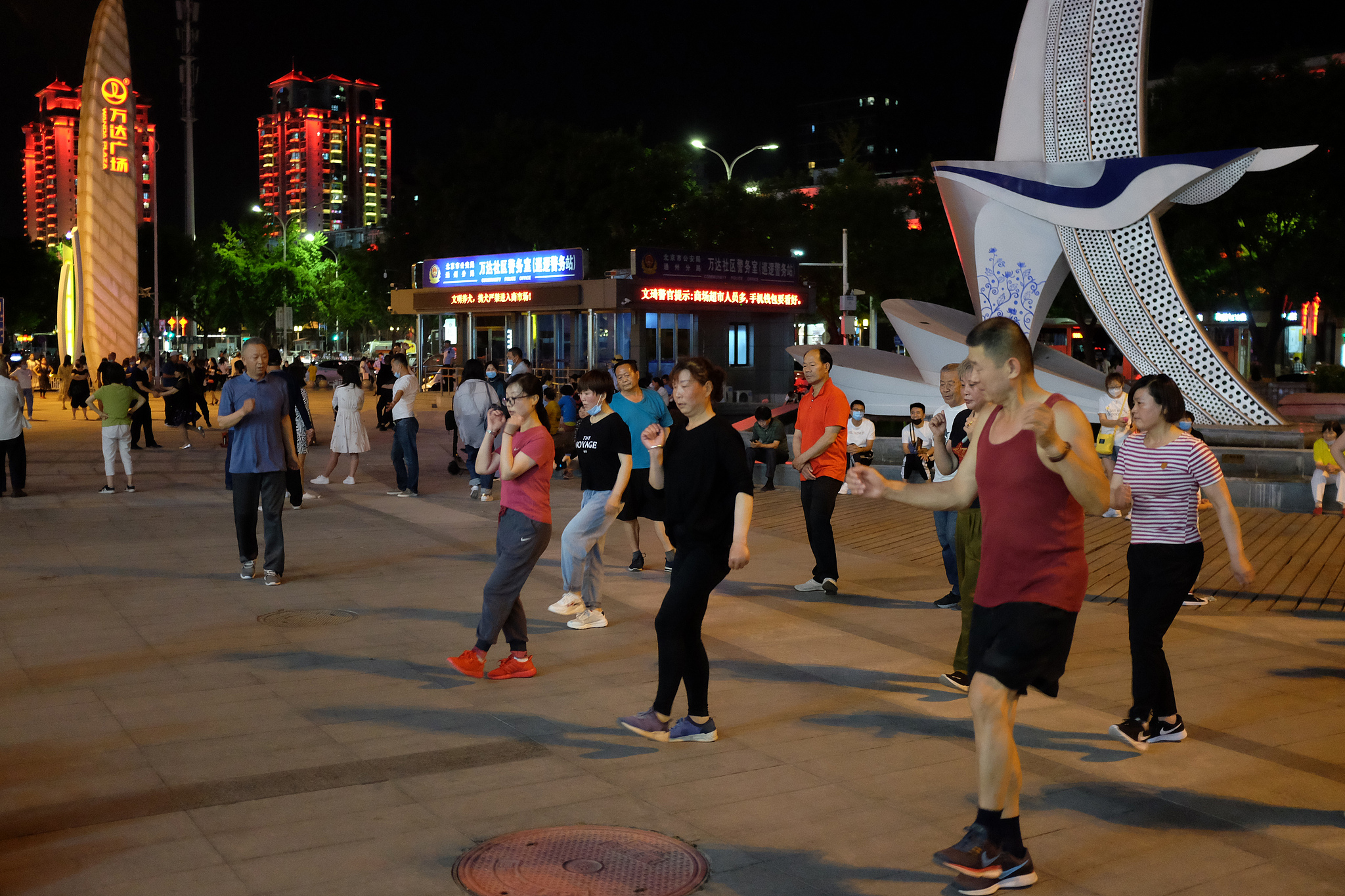 A public square transforms into a community gathering space as local residents join an evening dance routine after dinner. /VCG
