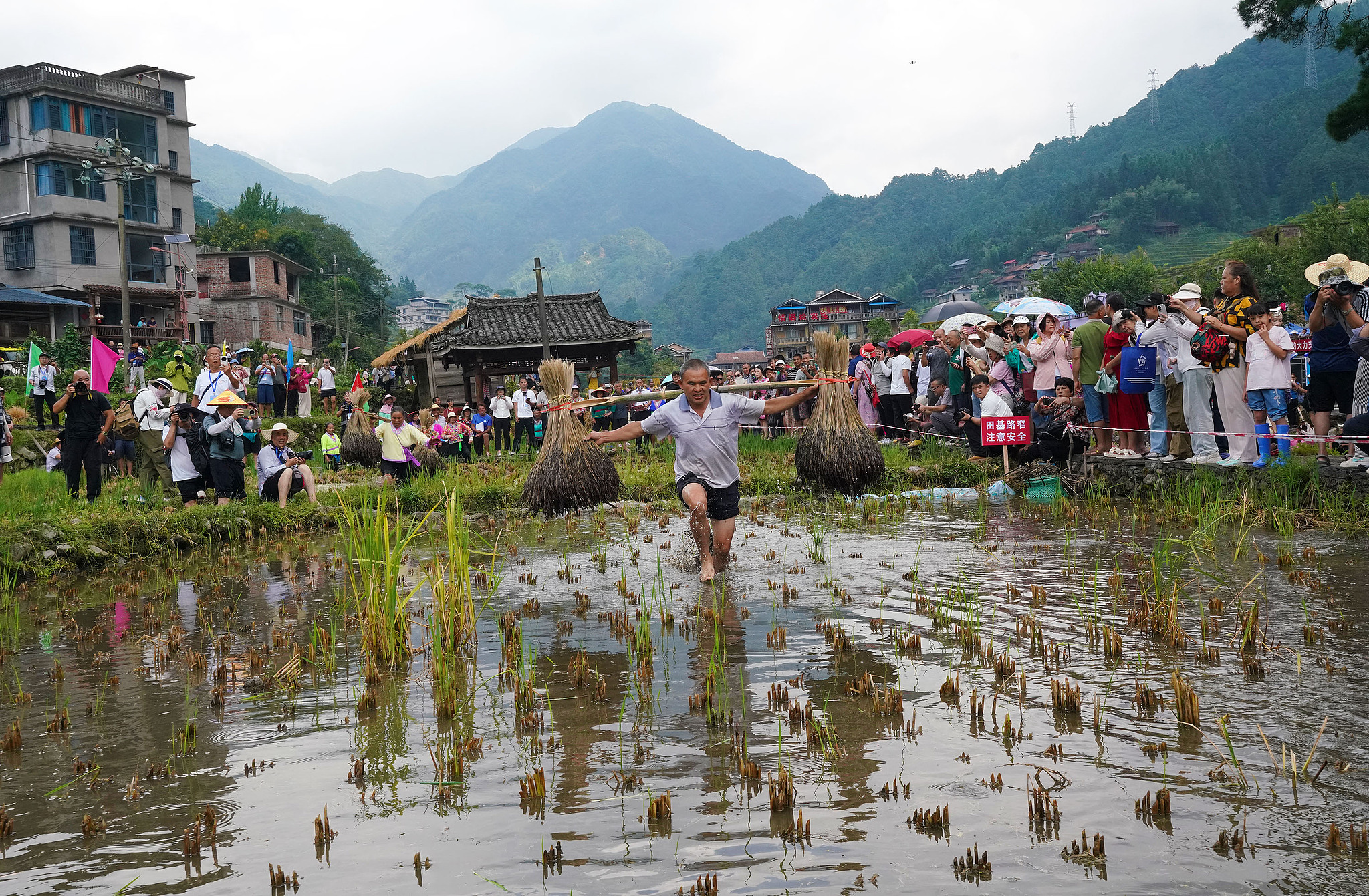 A relay race of carrying rice stalks is held to mark the 2026 Chinese Farmers' Harvest Festival in Peixiu Miao Village, Guangxi Zhuang Autonomous Region. /VCG