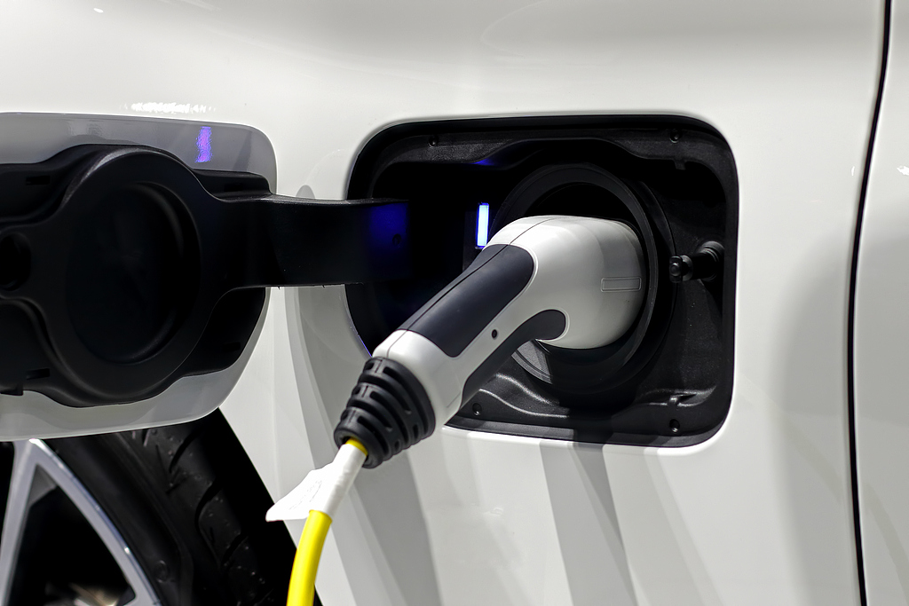 An electric vehicle is connected to a charging station. /VCG