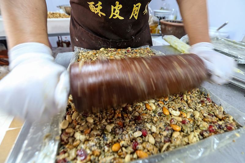 Veteran mooncake maker uses a rolling pin to press down prepared filling at a traditional workshop in Anyang, central China's Henan Province, on September 20, 2026. /VCG
