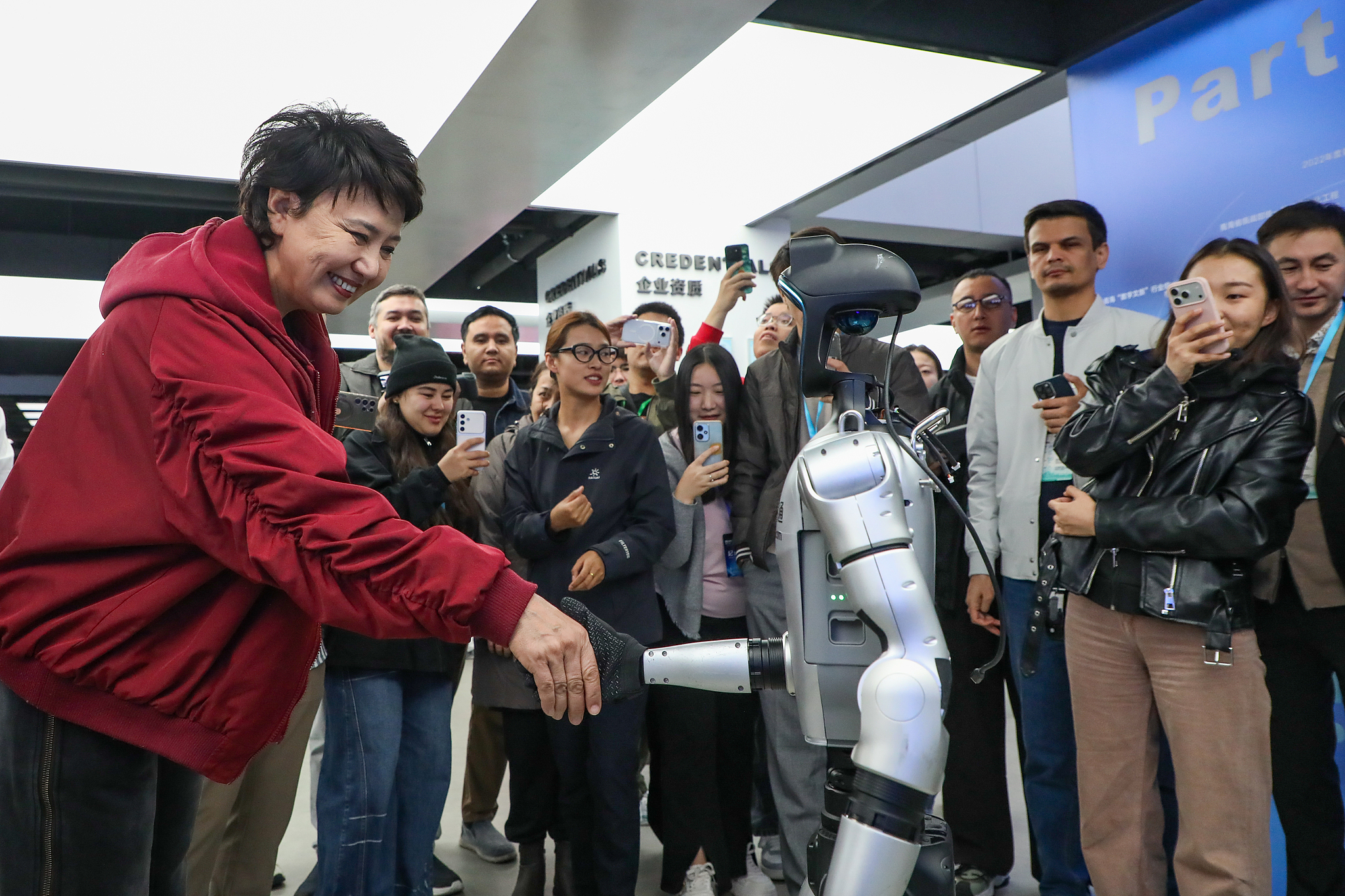 A visitor shakes hands with a humanoid robot at China Unicom's Sanjiangyuan Green Power & Intelligent Computing Integration Demonstration Park, Xining, Qinghai Province, China, September 19, 2026./ VCG
