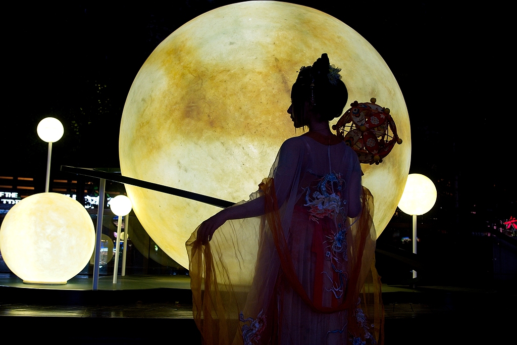 A woman in traditional dress poses in front of an art installation about moon on Nanjing East Road in Shanghai, east China, September 26, 2026. /VCG