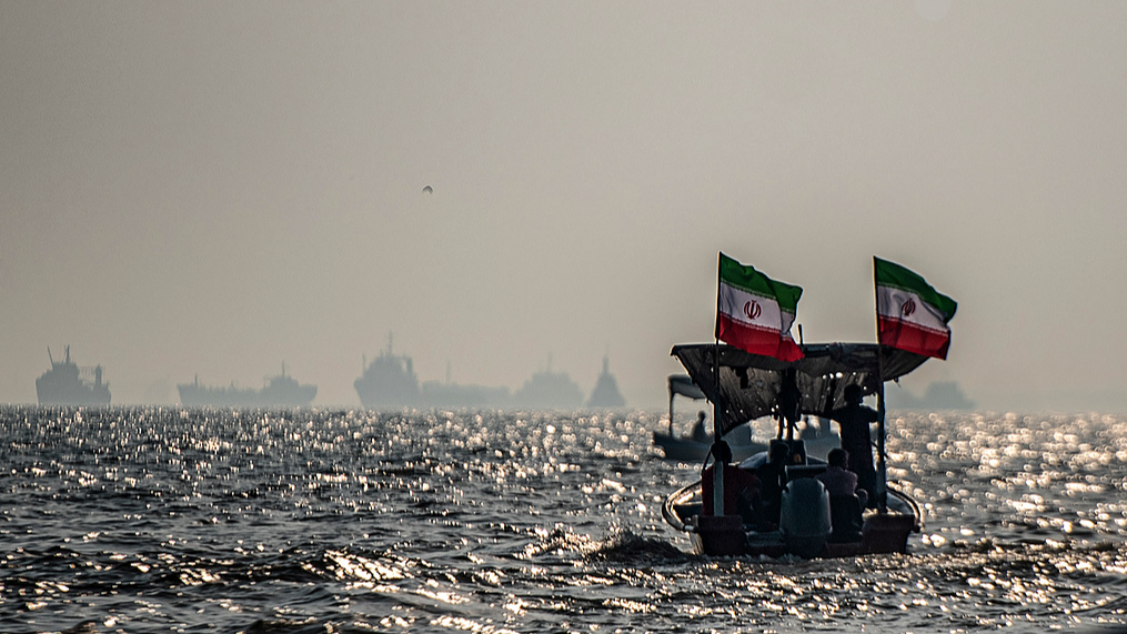 Commercial vessels are seen anchored offshore as small boats carrying members of Iran's paramilitary Basij Force take part in a military exercise along the Iranian coast overlooking the Strait of Hormuz, Iran, September 27, 2026. /VCG