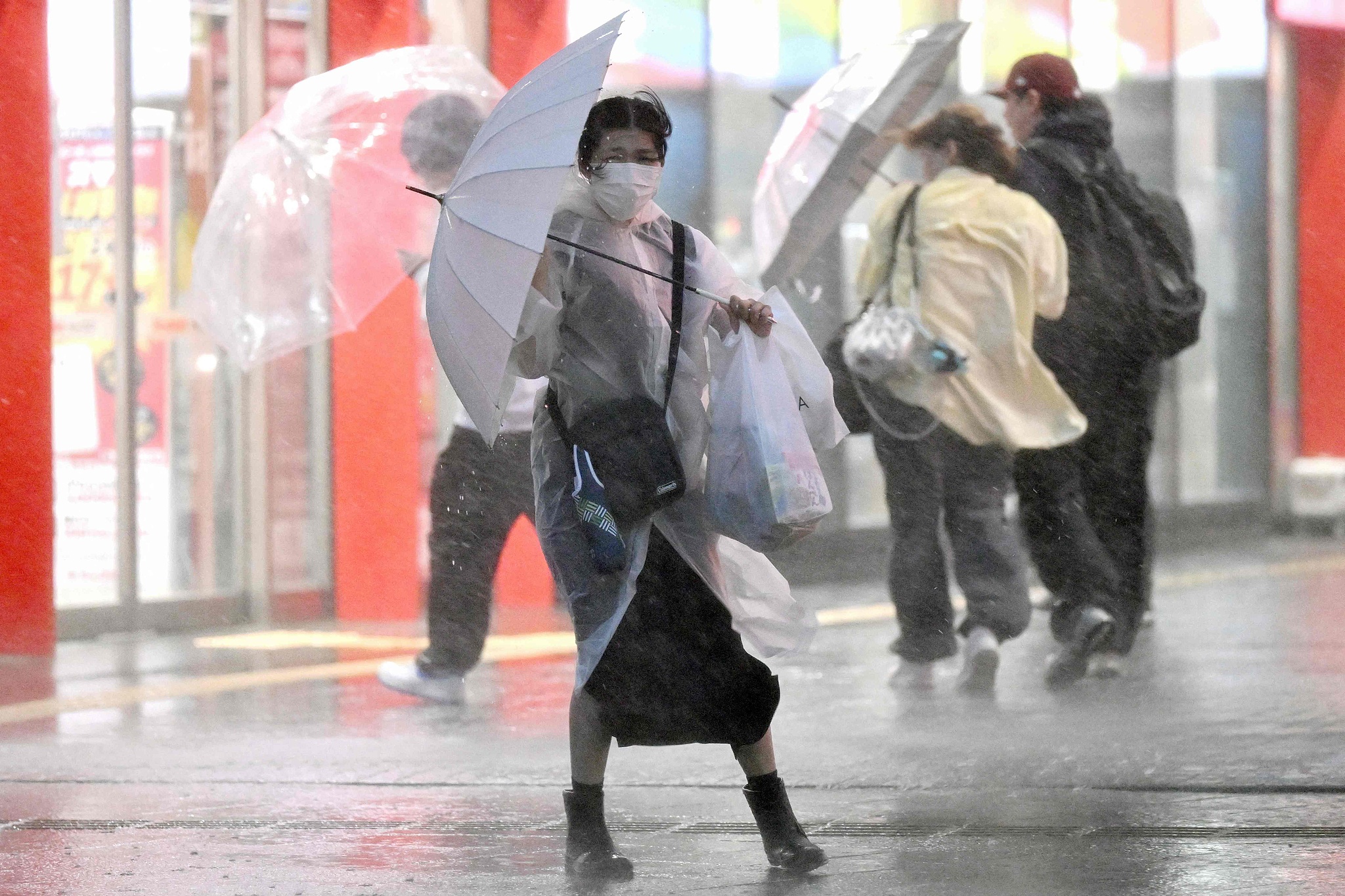 Pedestrians hold on to their umbrellas amid strong winds and heavy rainfall in Chiba, Japan, September 21, 2026. /VCG