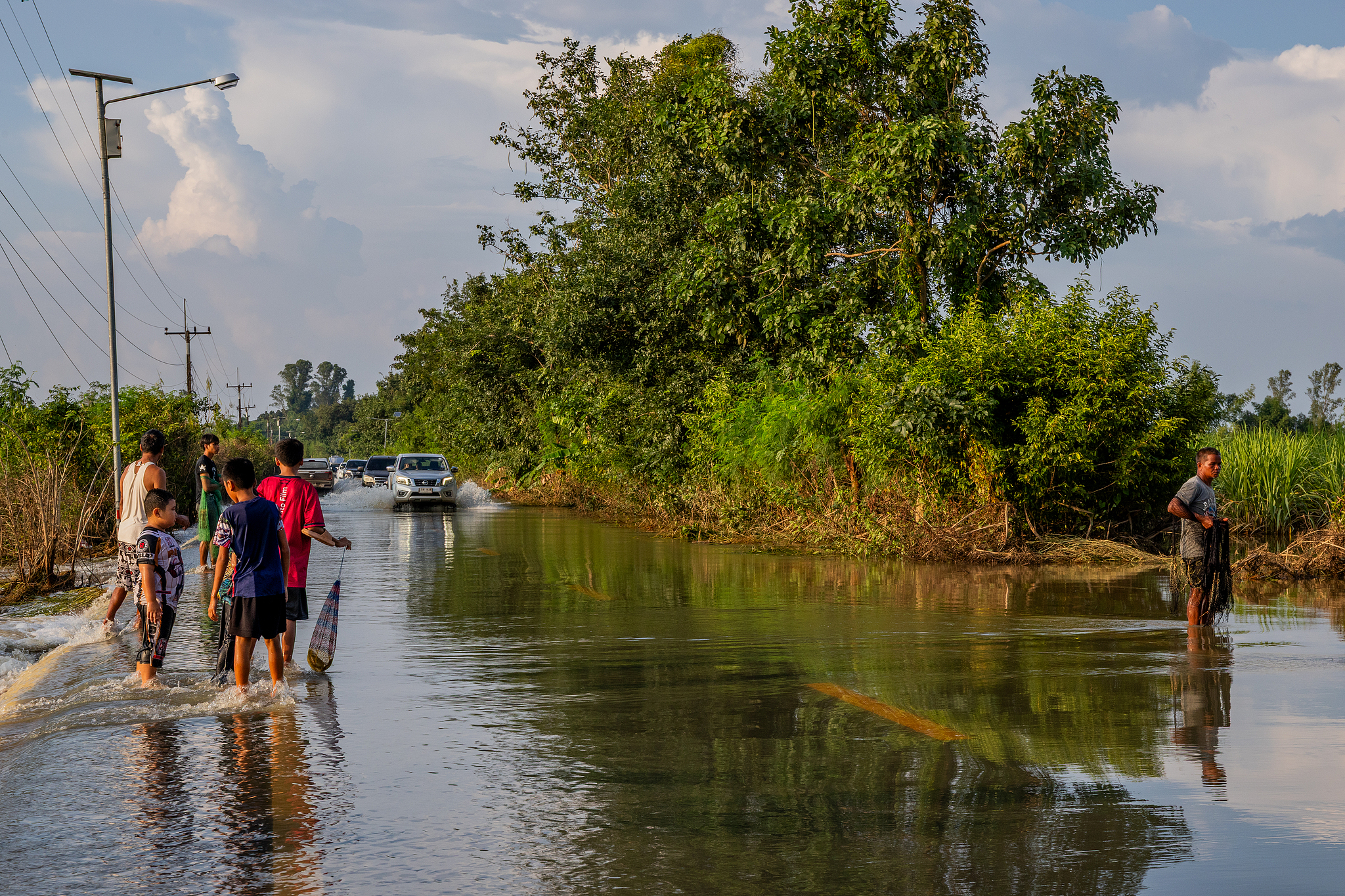 Locals fish for catfish on a flooded roadway in Sa Khwuan, Sa Kaeo Province, Thailand, as flooding continues across the country, September 30, 2026. /VCG