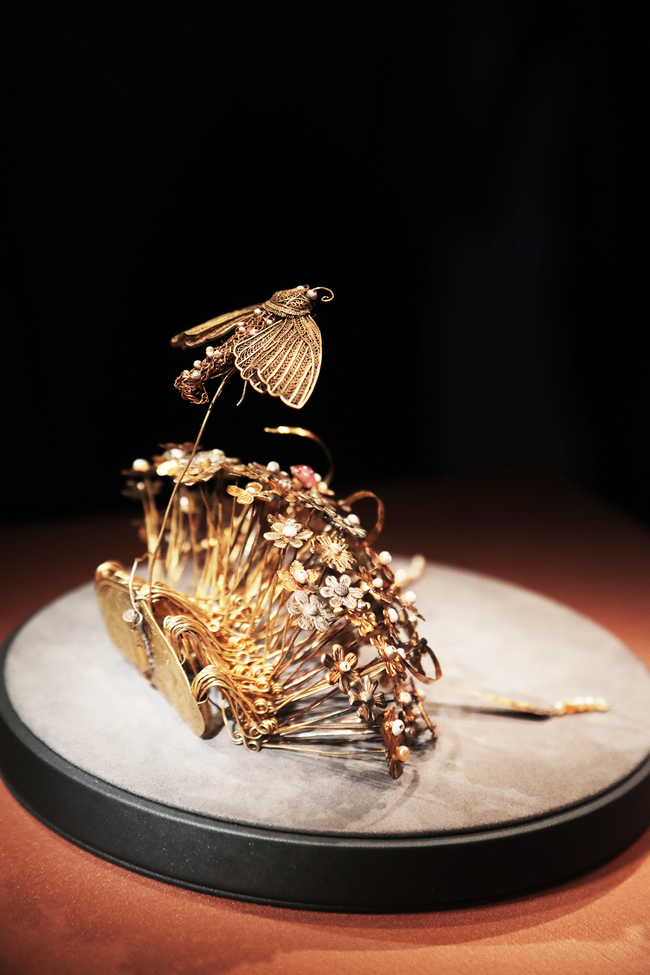 A gold hairpin from the Sui Dynasty featuring a cluster of flowers topped by a moth is seen on display at the National Museum of China in Beijing. /CGTN
