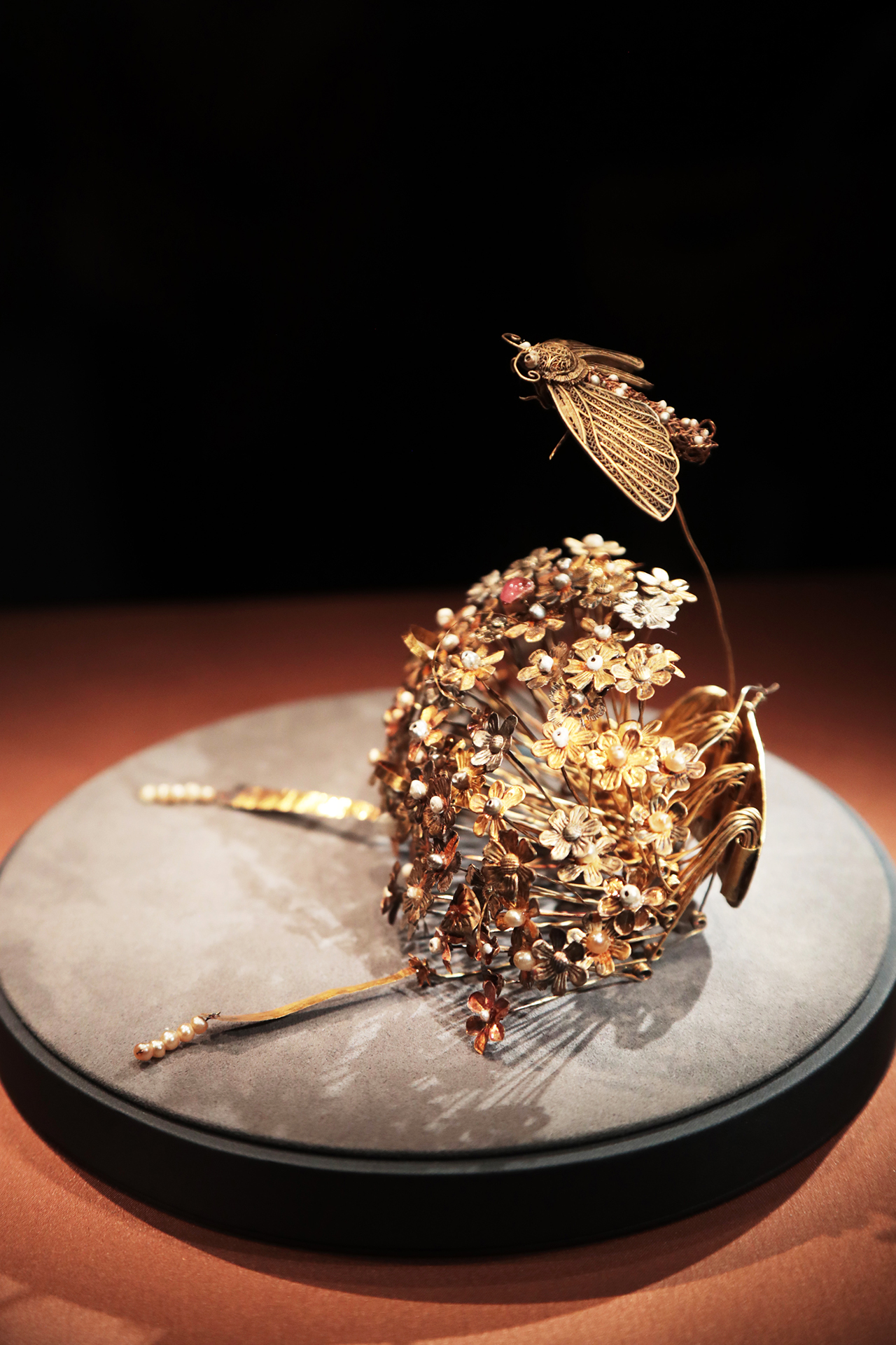 A gold hairpin from the Sui Dynasty featuring a cluster of flowers topped by a moth is seen on display at the National Museum of China in Beijing. /CGTN