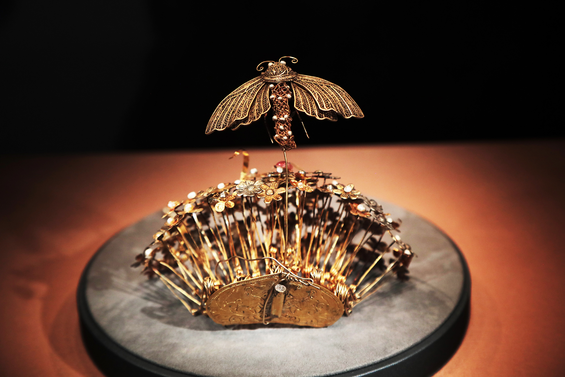 A gold hairpin from the Sui Dynasty featuring a cluster of flowers topped by a moth is seen on display at the National Museum of China in Beijing. /CGTN