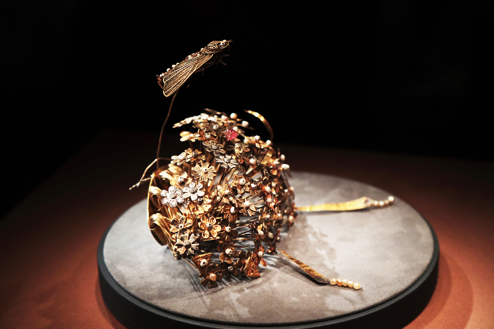 A gold hairpin from the Sui Dynasty featuring a cluster of flowers topped by a moth is seen on display at the National Museum of China in Beijing. /CGTN