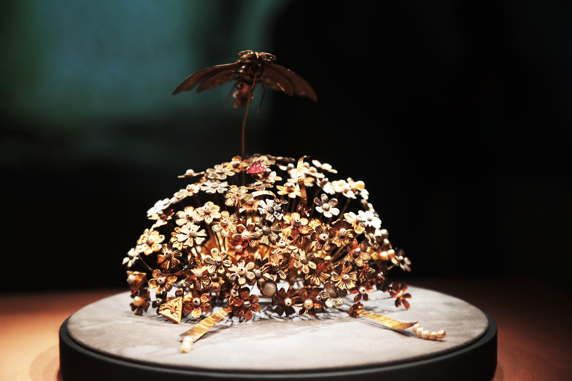 A gold hairpin from the Sui Dynasty featuring a cluster of flowers topped by a moth is seen on display at the National Museum of China in Beijing. /CGTN