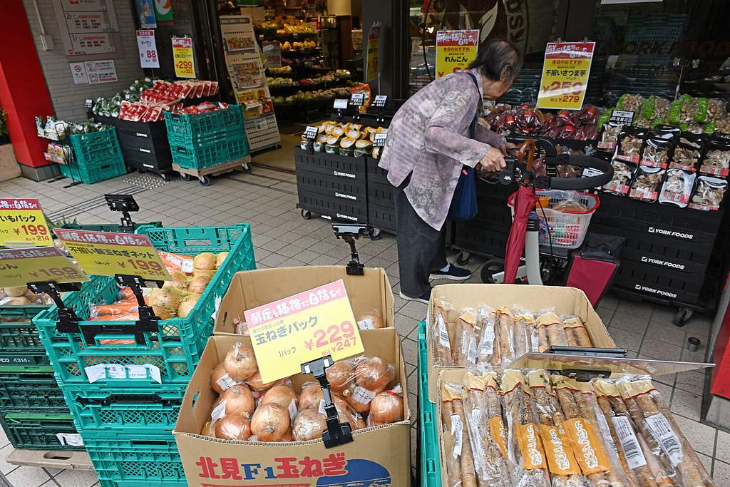 A morning shopper checks out vegetables at a shop in Tokyo. /VCG
