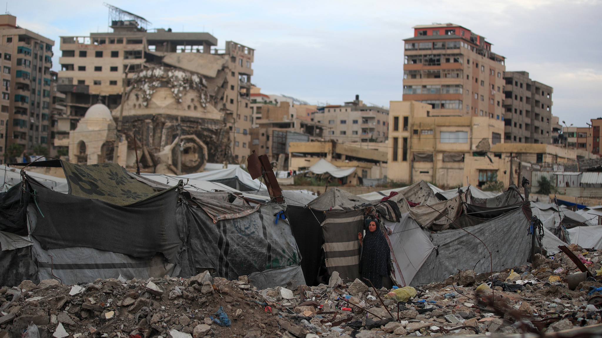 A Palestinian woman looks out from her tent in a displacement camp inside the port of Gaza City, Palestine, on October 5, 2026. / VCG