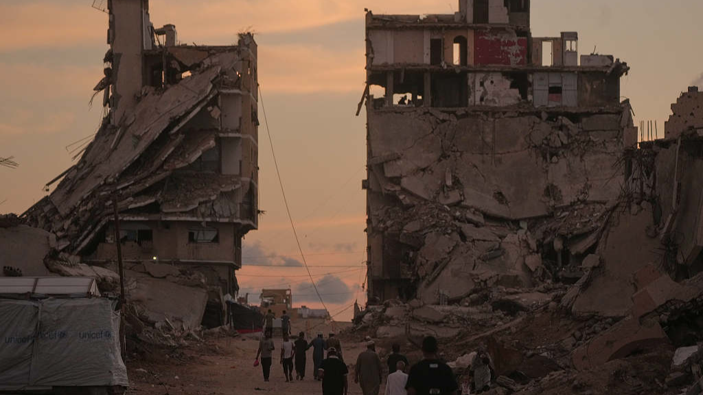 Palestinians walk along a street surrounded by buildings destroyed in Israeli military strikes during the Israel-Hamas conflict in Gaza, October 6, 2026. /VCG