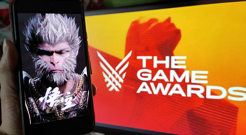 A gamer holds up a smartphone displaying a poster for Black Myth: Wukong during a livestream of The Game Awards (TGA) 2024 in Shanghai, China, December 13, 2024. /VCG