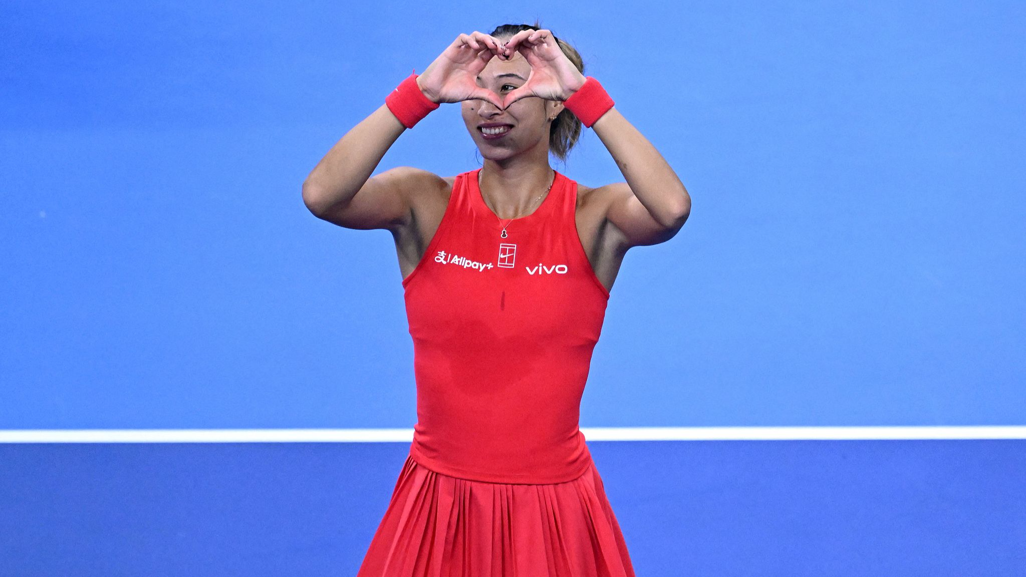 China's Zheng Qinwen makes a heart sign to show appreciation to the fans for their early 
