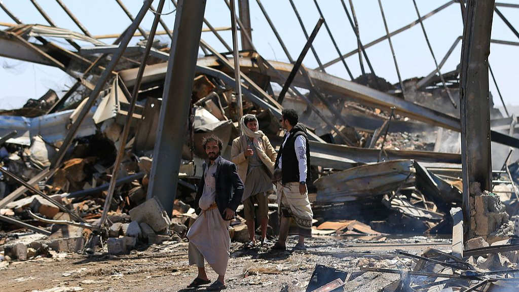 Yemeni men stand at the site of a reported overnight Saudi airstrike on a foam factory in Sanaa, Yemen, October 9, 2026. /VCG