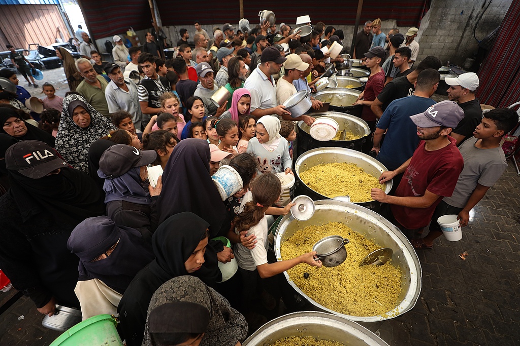 Palestinians, including children carrying cooking pots, gather to receive hot meals distributed in the Nuseirat Refugee Camp in Gaza City, Gaza, Palestine, September 28, 2026. /VCG