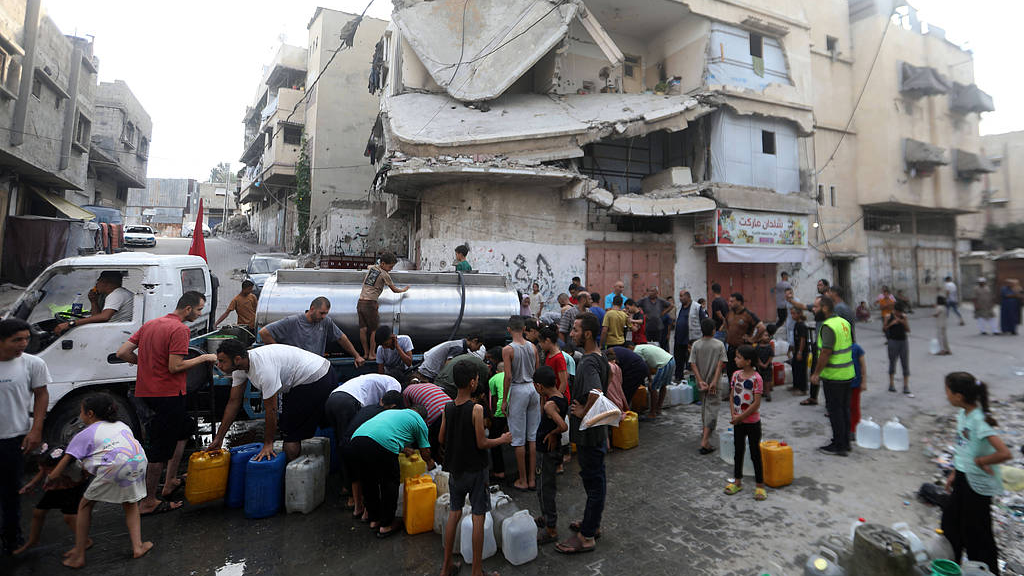 Displaced Palestinians gather to collect free water from a distribution truck near the Yellow Line east of Gaza City, Gaza, Palestine, August 18, 2026. /VCG
