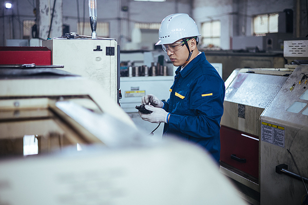 An engineer operates a CNC machine at an industrial unit in China. /VCG