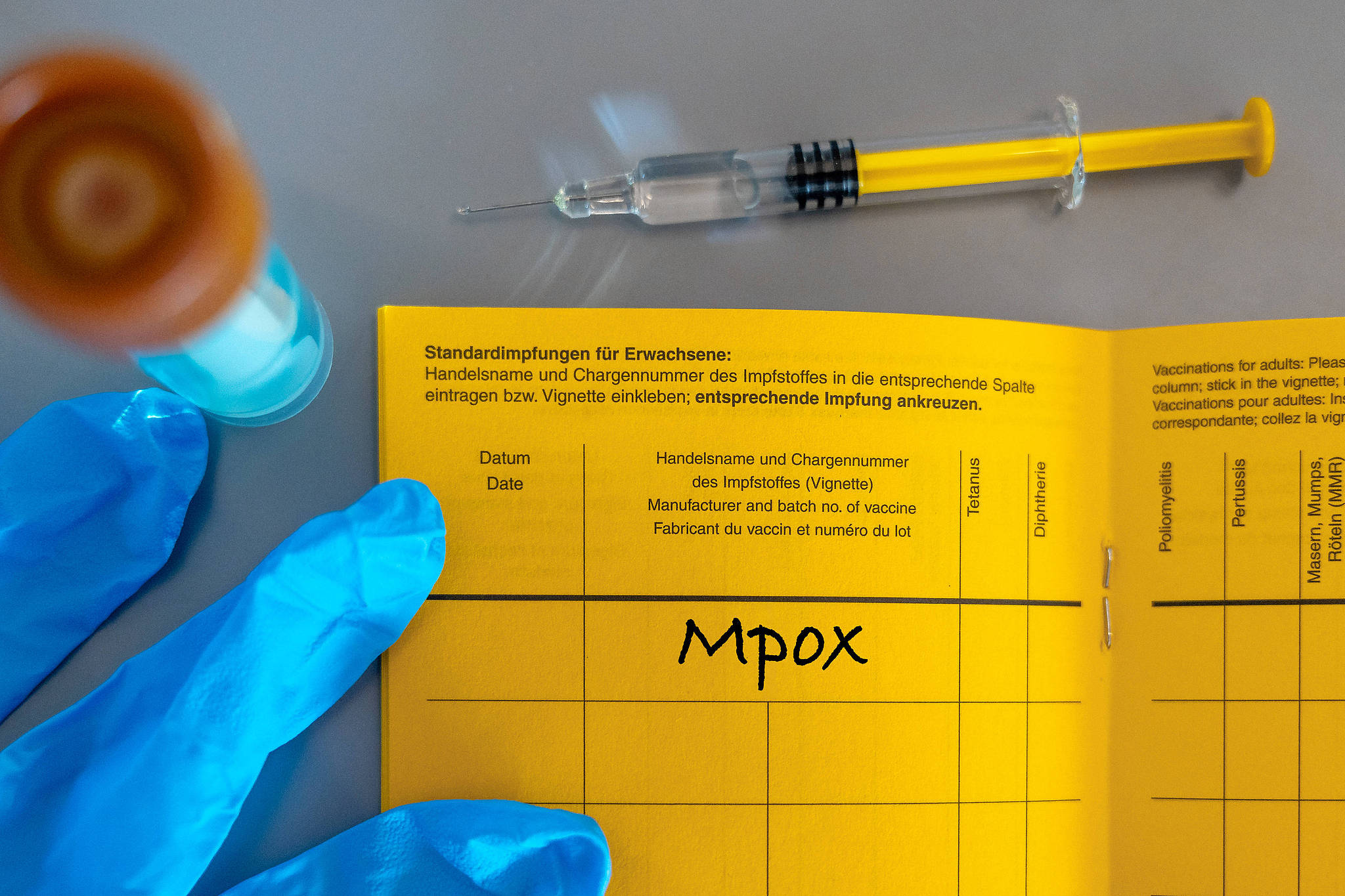 A syringe lies on a vaccination card marked 