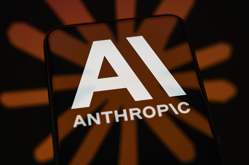 The Anthropic logo is displayed on a smartphone screen placed on a reflective surface, on which the Claude logo is projected in Creteil, France, April 21, 2026. /VCG