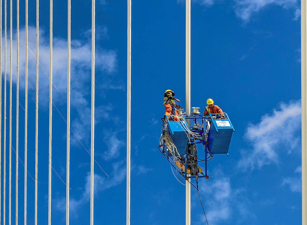 Workers wrap stay cables to protect them against corrosion on the Yongjiang Grand Bridge in Ningbo, Zhejiang Province, China, July 25, 2026. /VCG