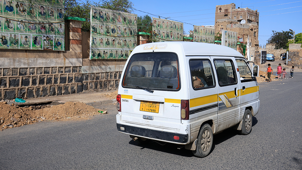 A minibus drives past a cemetery wall displaying portraits of slain Houthi fighters in Sanaa, Yemen, October 15, 2026. /VCG
