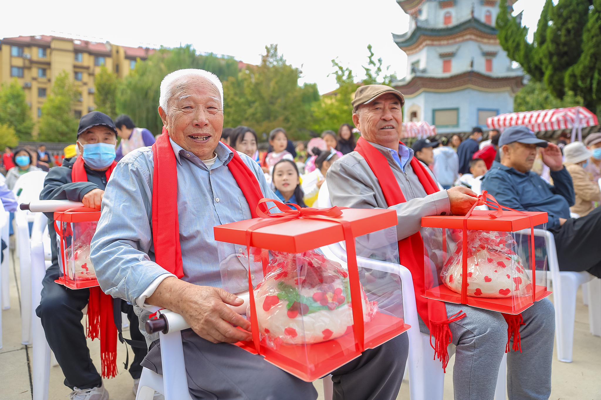 An elderly resident displays a peach-shaped longevity gift at the 7th Longevity Culture Festival in Yujiaxiahe Community, Qingdao City, east China's Shandong Province. /VCG