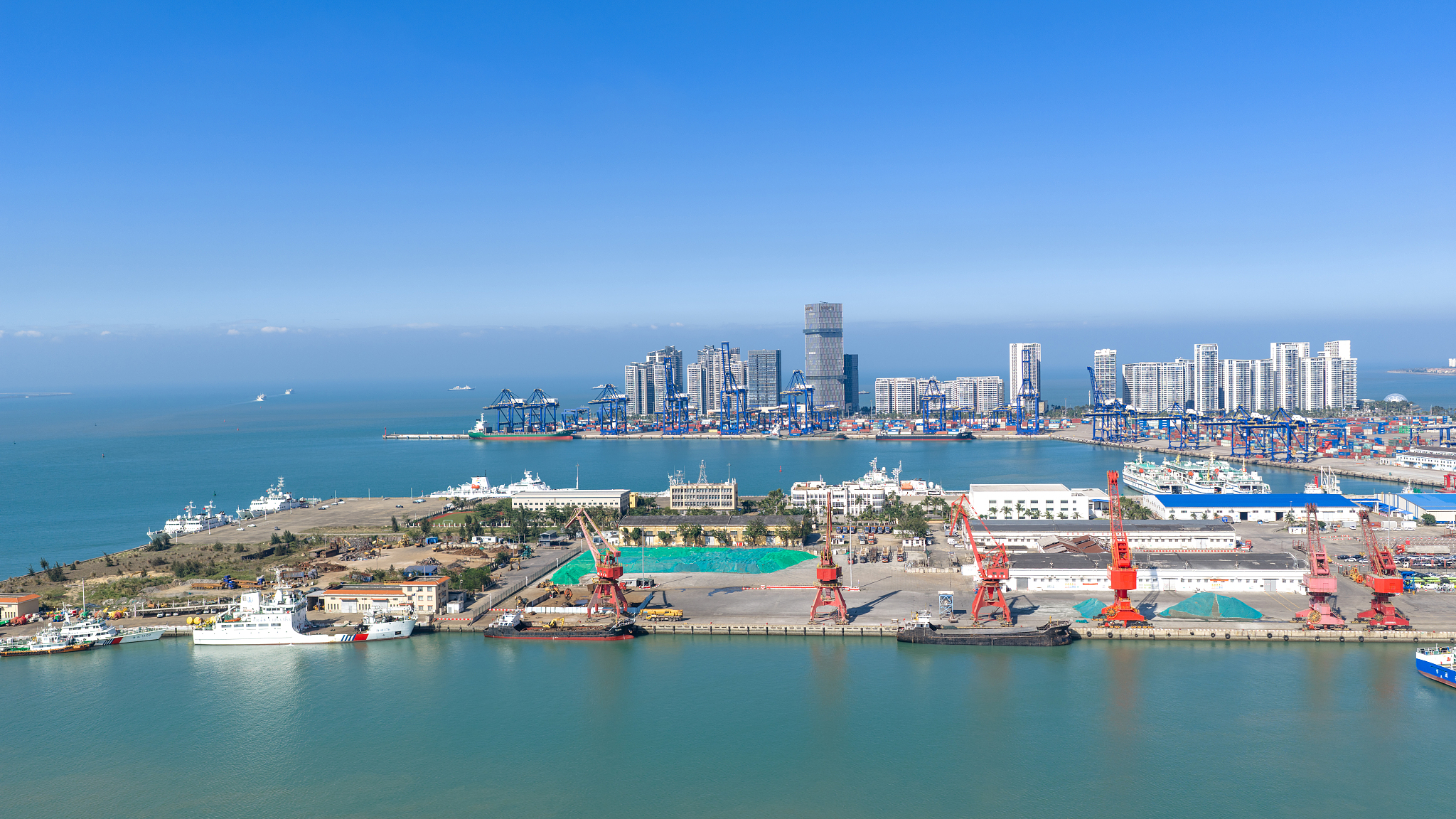 Aerial view of the container terminal at Haikou Port and the city skyline in Haikou, Hainan Province, December 21, 2025. /VCG