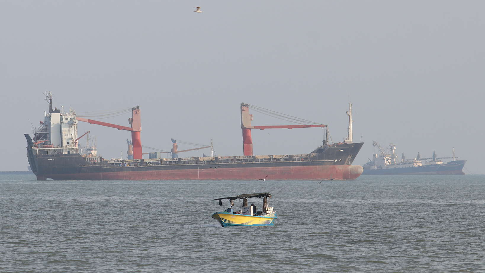 A boat floats as commercial vessels appear anchored in the Strait of Hormuz off Bandar Abbas, Iran, October 13, 2026. /VCG