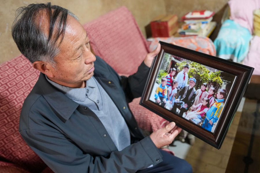 A villager shows a photograph of his father while telling students stories of the Long March in Hadaopu Township, Gansu Province, October 10, 2026. /Xinhua