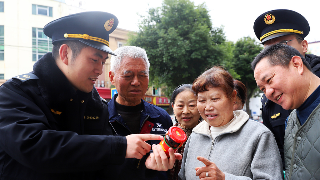 An official from local market regulation authorities tells local residents how to identify counterfeit goods in Taizhou City, east China's Zhejiang Province, March 9, 2026. /VCG