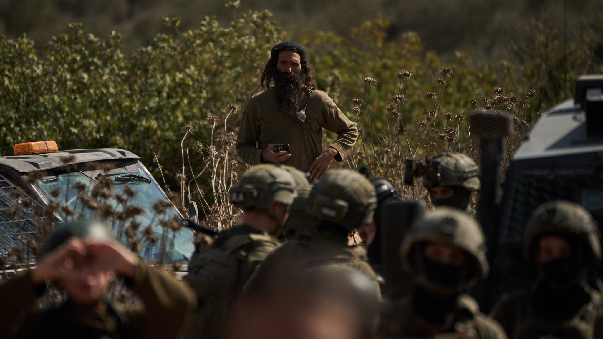 An Israeli settler overlooks members of Israeli forces blocking a road preventing Palestinians from harvesting olives in the West Bank, October 21, 2026. /VCG