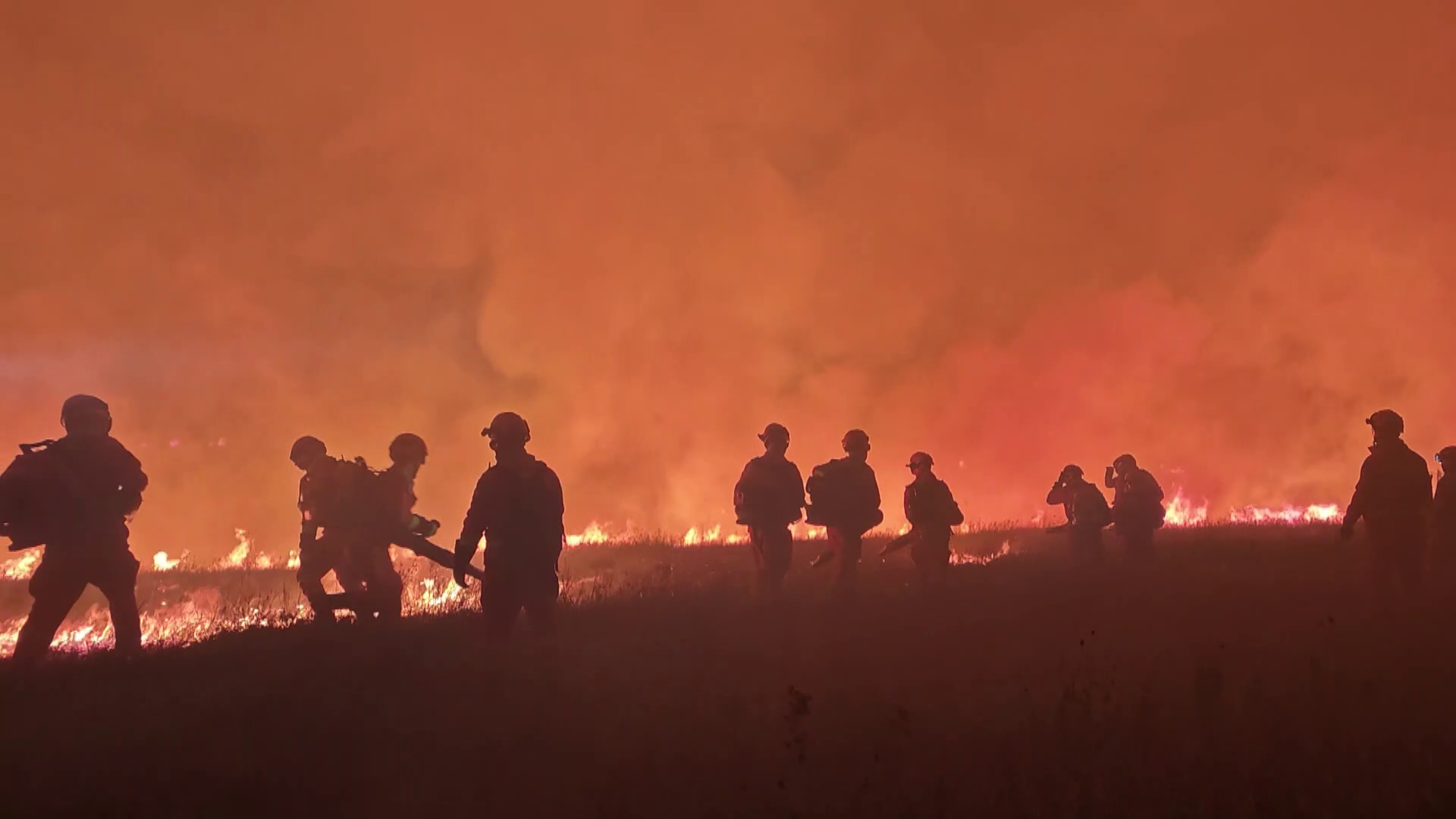 Firefighters battle a grassland fire along the border.
