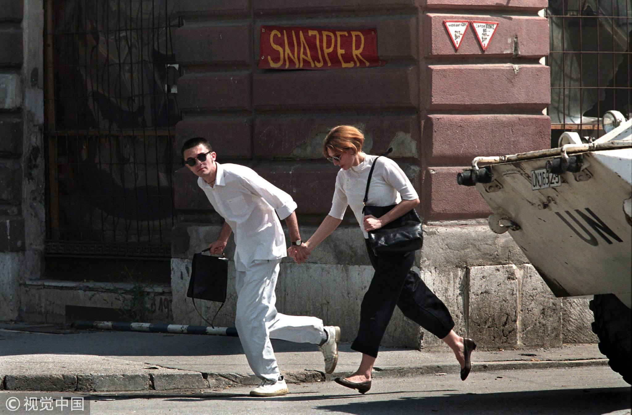 A young couple runs across the infamous Sniper Alley in Sarajevo, Bosnia, i...